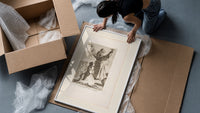 Kneeling woman praying before robed figure framed print being unpacked from protective bubble wrap and a box