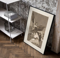 Winged demon carrying frightened figure poster in a black frame leaning beside a shelf in a raw-plaster loft