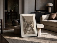 Winged demon carrying frightened figure print in a black frame leaning on a travertine table in a sunlit lounge