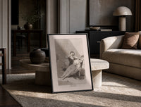 Man grieving over collapsed woman print in a black frame leaning on a travertine table in a sunlit lounge