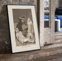 Two figures with locked faces attacked print in a black frame leaning beside a vintage door on parquet
