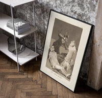 Two figures with locked faces attacked poster in a black frame leaning beside a shelf in a raw-plaster loft