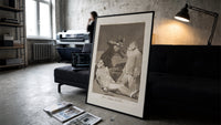 Two figures with locked faces attacked print in a slim black frame leaning on a dark sofa in a concrete print studio