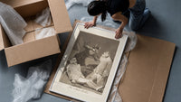 Two figures with locked faces attacked framed print being unpacked from protective bubble wrap and a box