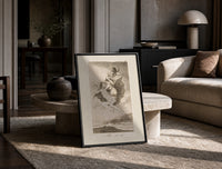 Witches flying with monkey demon print in a black frame leaning on a travertine table in a sunlit lounge