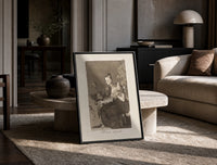 Grotesque figures spinning thread print in a black frame leaning on a travertine table in a sunlit lounge