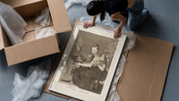 Grotesque figures spinning thread framed print being unpacked from protective bubble wrap and a box