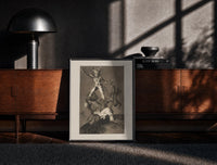 Black-framed Grotesque figures climbing atop one another print on a moody console with designer coffee-table books