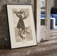 Flying woman above three men print in a black frame leaning beside a vintage door on parquet