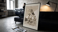 Grotesque demons and goat figure print in a slim black frame leaning on a dark sofa in a concrete print studio