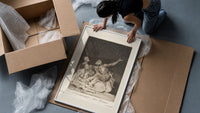 Grotesque nude figures under night sky framed print being unpacked from protective bubble wrap and a box