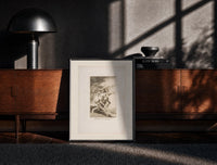 Black-framed Grotesque figures carrying woman aloft print on a moody console with designer coffee-table books