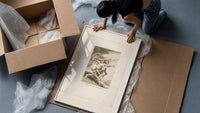 Grotesque figures carrying woman aloft framed print being unpacked from protective bubble wrap and a box