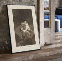 struggling figures with flying witches print in a black frame leaning beside a vintage door on parquet