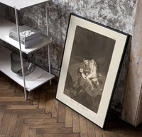 struggling figures with flying witches poster in a black frame leaning beside a shelf in a raw-plaster loft