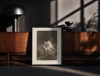 Black-framed struggling figures with flying witches print on a moody console with designer coffee-table books