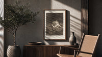 struggling figures with flying witches poster framed above a fluted sideboard beside an olive tree
