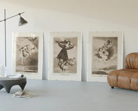 Goya witches flying etchings triptych displayed beside a brown leather sofa