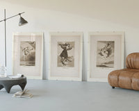 Goya witches flying etchings triptych three-panel set displayed beside a brown leather sofa