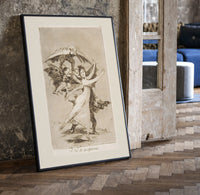 Woman fleeing winged demons print in a black frame leaning beside a vintage door on parquet