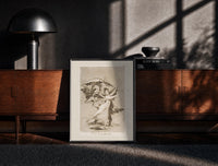 Black-framed Woman fleeing winged demons print on a moody console with designer coffee-table books