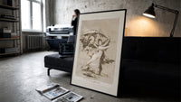 Woman fleeing winged demons print in a slim black frame leaning on a dark sofa in a concrete print studio
