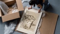 Woman fleeing winged demons framed print being unpacked from protective bubble wrap and a box