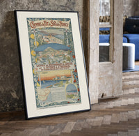 French Riviera coastal town views print in a black frame leaning beside a vintage door on parquet