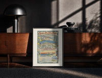 Black-framed French Riviera coastal town views print on a moody console with designer coffee-table books