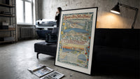 French Riviera coastal town views print in a slim black frame leaning on a dark sofa in a concrete print studio