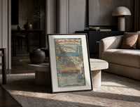 French Riviera coastal town views print in a black frame leaning on a travertine table in a sunlit lounge