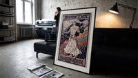 Joan of Arc in armor print in a slim black frame leaning on a dark sofa in a concrete print studio