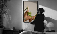 Green Woven Stiletto Sandals print in a slim black frame being hung on a sunlit wall in a monochrome room