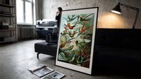 Colorful hummingbirds among tropical foliage print in a slim black frame leaning on a dark sofa in a concrete print studio