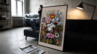 Botanical illustration of various orchids print in a slim black frame leaning on a dark sofa in a concrete print studio