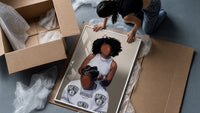 Hair Braiding Scene with Two Figures framed print being unpacked from protective bubble wrap and a box