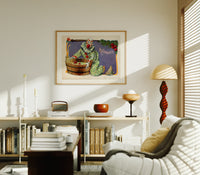 Clown bobbing for apples print in an oak frame above a mid-century book console with a vintage radio
