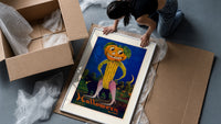 Anthropomorphic pumpkin-headed corn figure framed print being unpacked from protective bubble wrap and a box