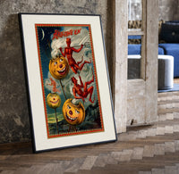 Grinning jack-o-lantern pumpkins with red devils print in a black frame leaning beside a vintage door on parquet