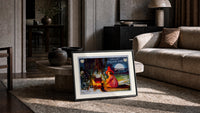 Witch girl sitting by cauldron fire print in a slim black frame leaning on a travertine coffee table