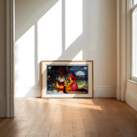 Witch girl sitting by cauldron fire print in an oak frame on a sunlit wood floor beneath tall window light