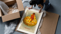 Red devil sitting on jack-o-lantern framed print being unpacked from protective bubble wrap and a box