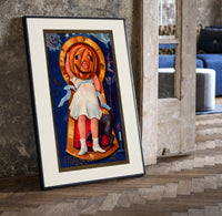 Girl with jack-o'-lantern pumpkin head print in a black frame leaning beside a vintage door on parquet