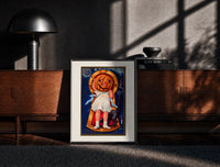 Black-framed Girl with jack-o'-lantern pumpkin head print on a moody console with designer coffee-table books