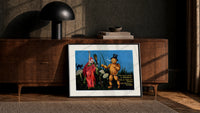 Witch and pumpkin man walking print in a black frame leaning against a walnut console in lamplight