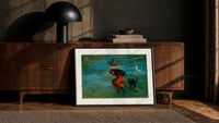 Witch flying on broom with black cat print in a black frame leaning against a walnut console in lamplight