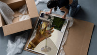 Raised Wine Glass framed print being unpacked from protective bubble wrap and a box