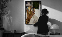 Raised Wine Glass print in a slim black frame being hung on a sunlit wall in a monochrome room