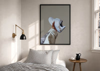 White Sneaker with Gold Chains print in a black frame above a bed with striped linens, a brass wall lamp and a sunlit window