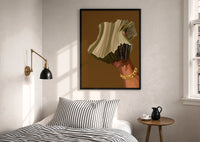 Hand Holding Fanned Cash print in a black frame above a bed with striped linens, a brass wall lamp and a sunlit window